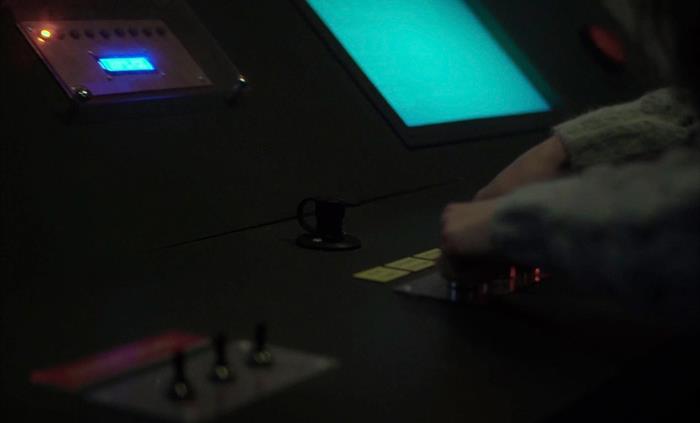 A panel with a red light is pictured above several knobs and switches being played with in an escape room setting.